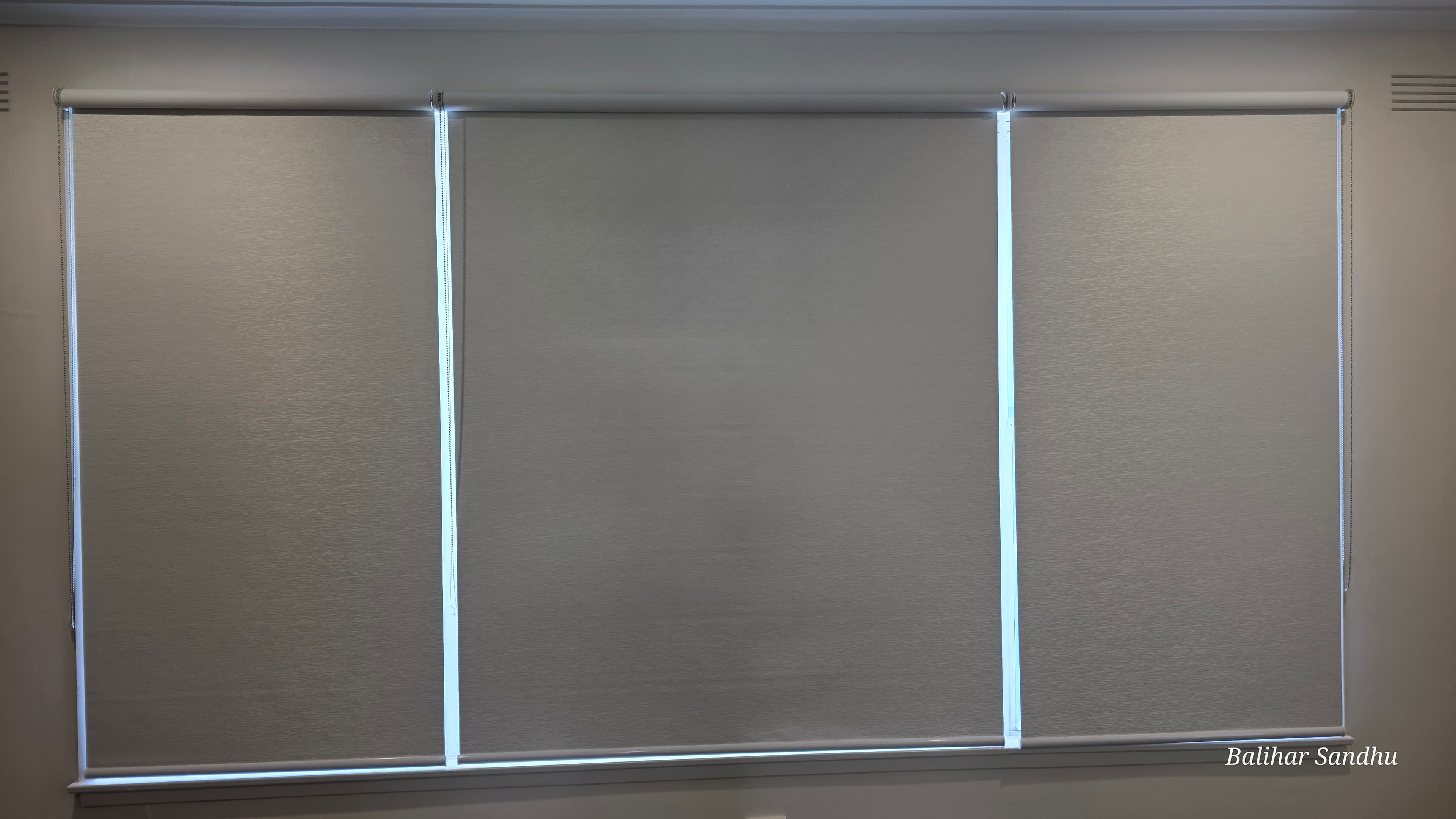 Triple blockout roller blinds installed on a wide bay window