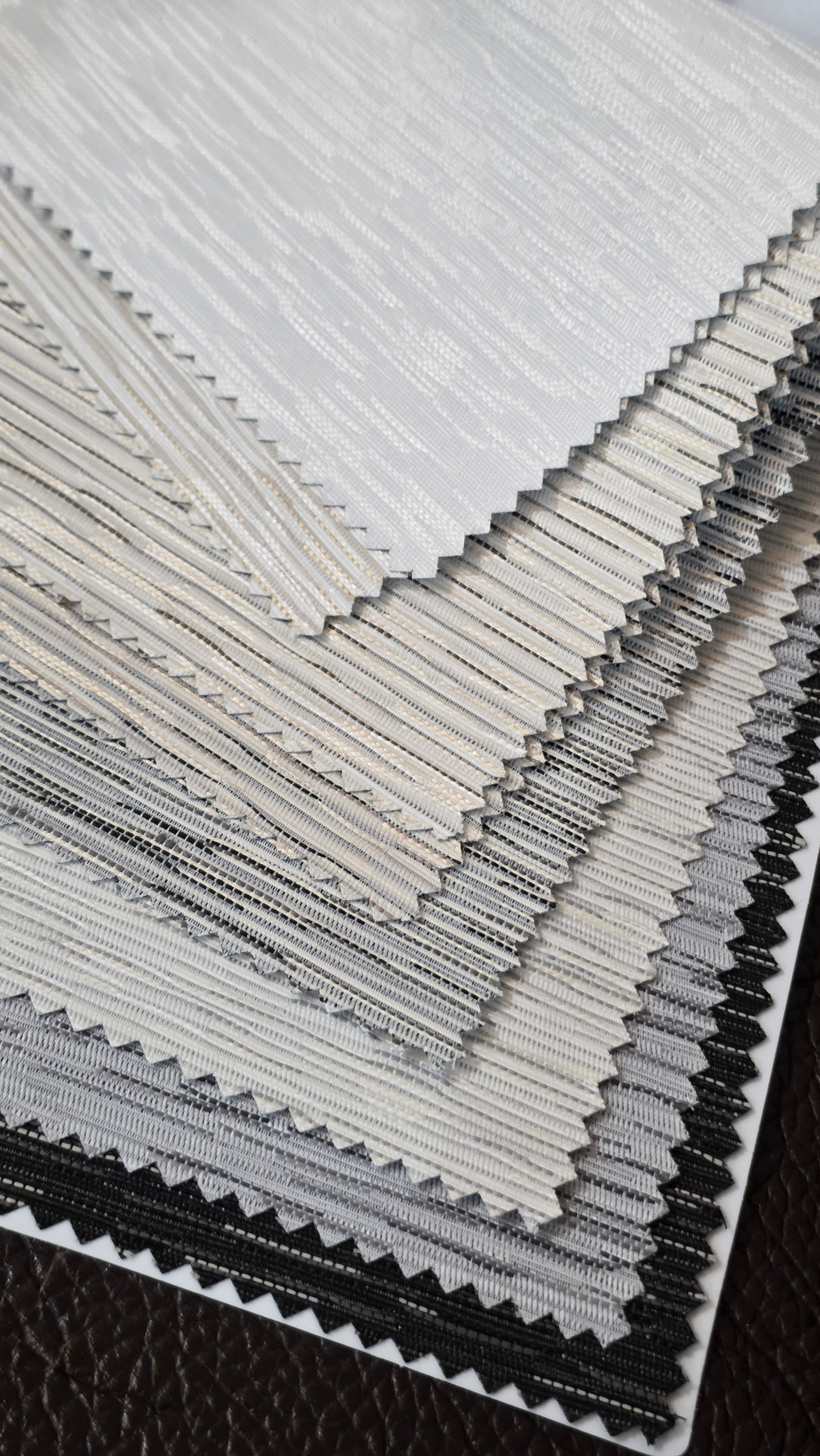 Fabric swatch samples fanned out — from sheer white through to charcoal blockout